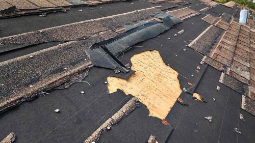 Damaged plywood roof decking beneath shingles
