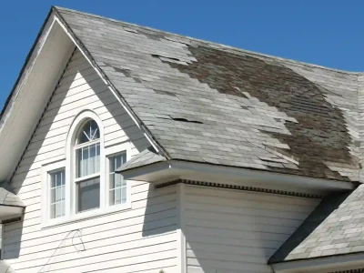 Home with severely peeling shingles from delayed roof repairs in Northwest Arkansas