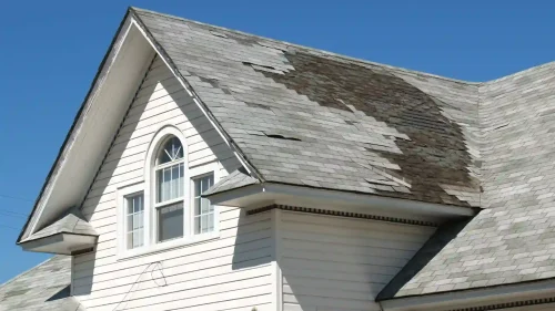 Home with severely peeling shingles from delayed roof repairs in Northwest Arkansas