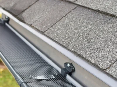 Roofer inspecting residential gutters on a Fayetteville home roof edge