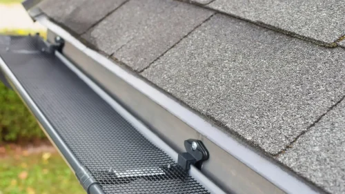 Roofer inspecting residential gutters on a Fayetteville home roof edge