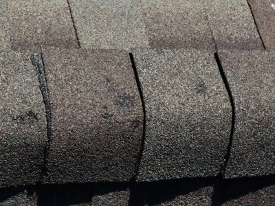 Dented roof shingle showing signs of hail damage