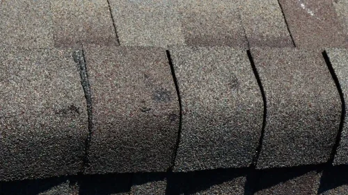 Dented roof shingle showing signs of hail damage