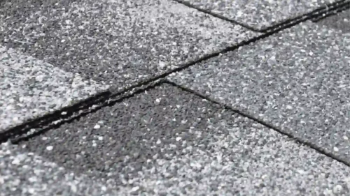 Weathered roof shingles with white residue and granule loss indicating hidden water damage in Northwest Arkansas