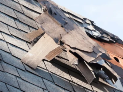 Roof with shingles torn away by high winds exposing decking in Northwest Arkansas