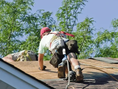 Roofer inspecting asphalt shingles on a residential roof