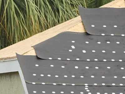 Synthetic roof underlayment laid over plywood decking during roof preparation