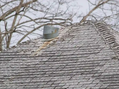 Weathered and warped asphalt shingles showing damage from freeze-thaw temperature cycles in Northwest Arkansas
