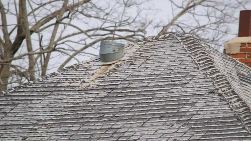 Weathered and warped asphalt shingles showing damage from freeze-thaw temperature cycles in Northwest Arkansas