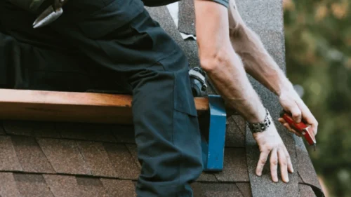 Roofer securing and preparing asphalt shingles for storm season in Northwest Arkansas